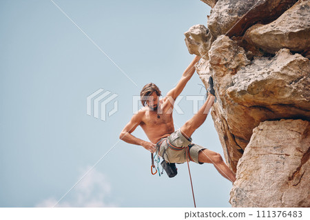 Mountain or rock climbing, cliff hanging and adrenaline junkie out on adventure and checking his safety equipment, hook and rope. Fearless man doing fitness, exercise and workout during extreme sport 111376483