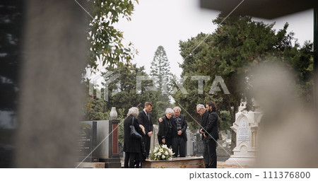 People at a funeral, death and graveyard with family mourning outdoor, grief and loss with coffin. Cemetery, ceremony and sad, goodbye and burial service with support, comfort and empathy at memorial 111376800