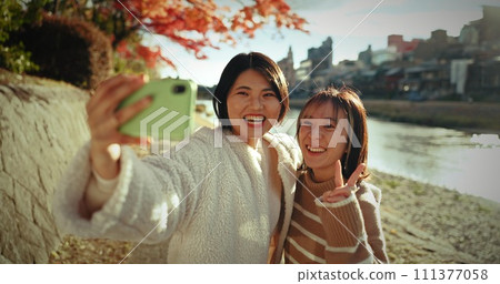 Japanese women, friends and happy in selfie, nature and lake with web blog, post and excited on vacation. Girl group, photography and memory with profile picture, live stream or social media in Tokyo Japanese women, friends and happy in selfie, nature and lake with web blog, post and excited on vacation. Girl group, photography and memory with profile picture, live stream or social media in Tokyo 111377058