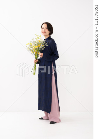 A woman wearing an ao dai and holding a bouquet of flowers A woman wearing an ao dai and holding a bouquet of flowers 111378053