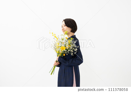 A woman wearing an ao dai and holding a bouquet of flowers 111378058