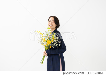 A woman wearing an ao dai and holding a bouquet of flowers 111378061