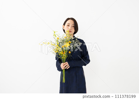 A woman wearing an ao dai and holding a bouquet of flowers 111378199