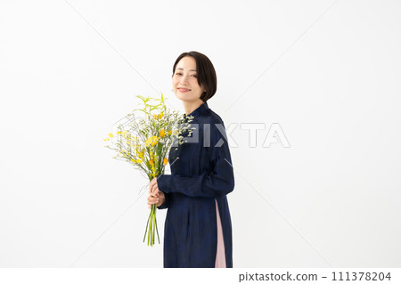 A woman wearing an ao dai and holding a bouquet of flowers 111378204