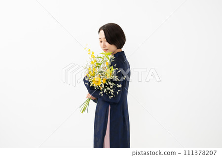 A woman wearing an ao dai and holding a bouquet of flowers 111378207