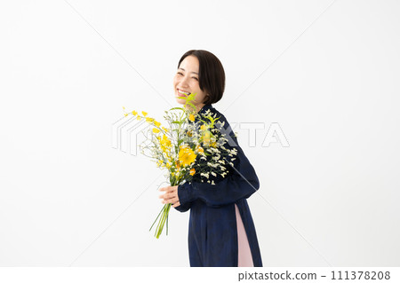 A woman wearing an ao dai and holding a bouquet of flowers 111378208