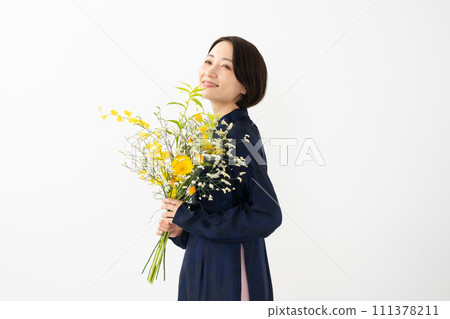 A woman wearing an ao dai and holding a bouquet of flowers 111378211
