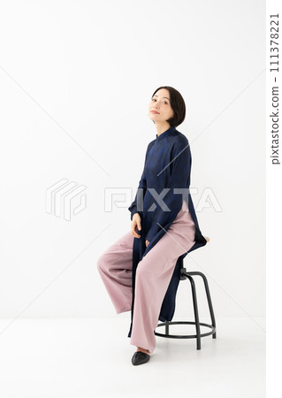 A woman wearing Ao Dai sits down A woman wearing Ao Dai sits down 111378221