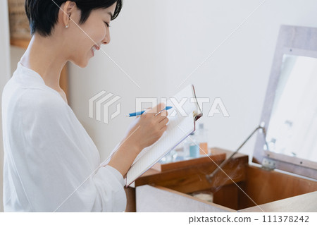 一位女士在她房間的筆記本上寫下她的計劃 111378242