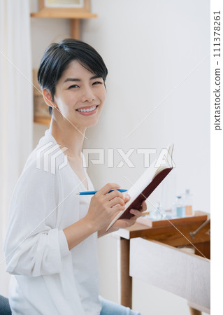 一位女士在她房間的筆記本上寫下她的計劃 111378261