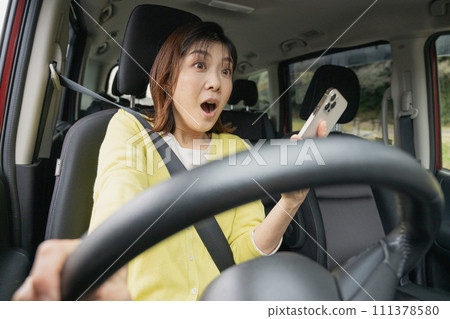 A woman who drives while looking at her smartphone and is surprised when she almost collides with her car 111378580