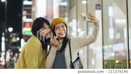 Friends, Japanese and selfie with women, smile and excited with blog post, memory and social media. People, smartphone or girls in a street, night and picture with pose, cheerful and bonding together Friends, Japanese and selfie with women, smile and excited with blog post, memory and social media. People, smartphone or girls in a street, night and picture with pose, cheerful and bonding together 111379140