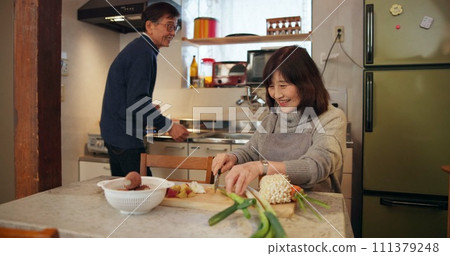 Cooking, conversation and Japanese couple in kitchen cutting vegetables for meal, dinner or lunch. Happy, talking and senior man and woman preparing food for supper together with produce at home. 111379248