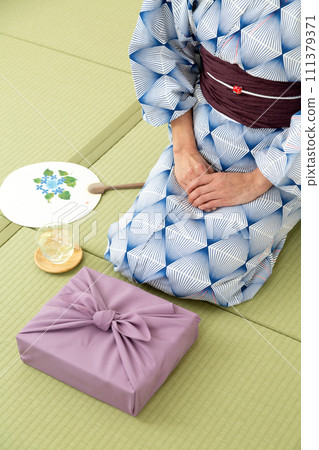 A middle-aged woman in a yukata sitting on a tatami mat in a Japanese-style room and a wrapping cloth as a mid-year gift 111379371