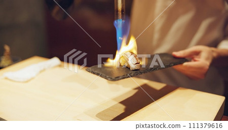 Hands, fire and cooking sushi with chef in restaurant for traditional Japanese food or cuisine closeup. Kitchen, flame for seafood preparation and person working with gourmet meal recipe ingredients Hands, fire and cooking sushi with chef in restaurant for traditional Japanese food or cuisine closeup. Kitchen, flame for seafood preparation and person working with gourmet meal recipe ingredients 111379616