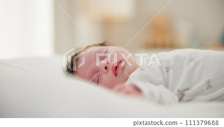 Tired, sleeping and newborn baby on a bed at a home in the bedroom for resting and dreaming. Cute, sweet and little infant, child or kid taking a nap in the morning in the nursery at family house. 111379688