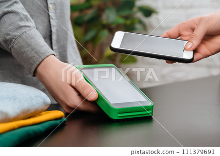 Contactless payment with smartphone and nfc terminal in clothes shop Contactless payment with smartphone and nfc terminal in clothes shop 111379691