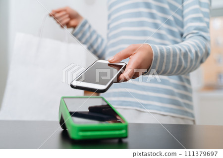 Young woman making mobile payment with her smartphone in shop Young woman making mobile payment with her smartphone in shop 111379697