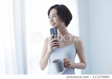 Young woman relaxing with a smartphone Young woman relaxing with a smartphone 111379869