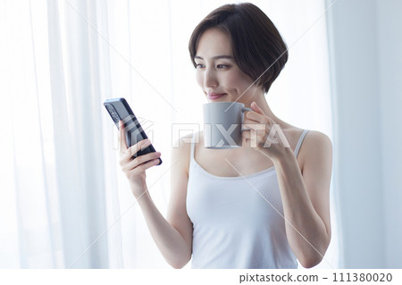 Young woman relaxing with a smartphone Young woman relaxing with a smartphone 111380020