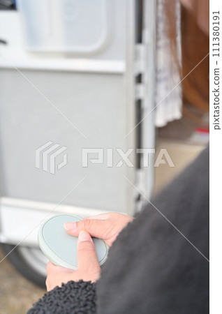 一名年輕女子在冬季露營旅行期間用暖手器(可充電暖爐)暖手 一名年輕女子在冬季露營旅行期間用暖手器(可充電暖爐)暖手 111380191