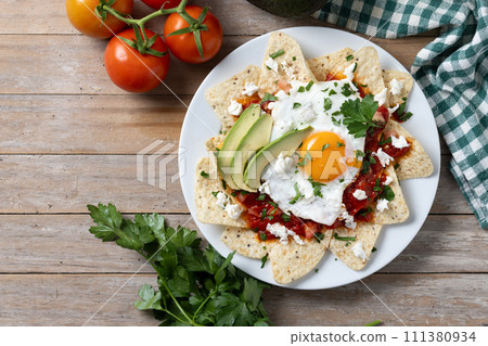 Traditional Mexican chilaquiles breakfast on wooden table Traditional Mexican chilaquiles breakfast on wooden table 111380934