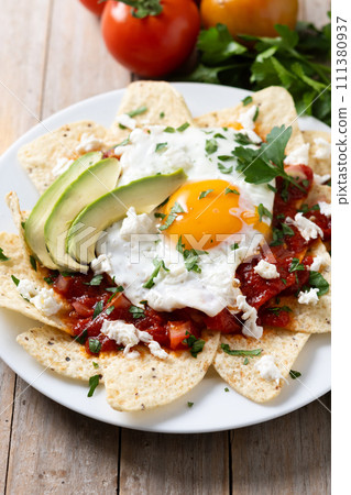Traditional Mexican chilaquiles breakfast on wooden table 111380937