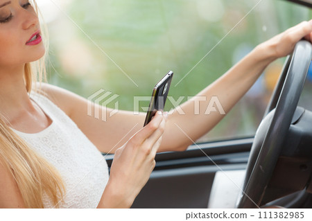 Woman using phone while driving her car 111382985
