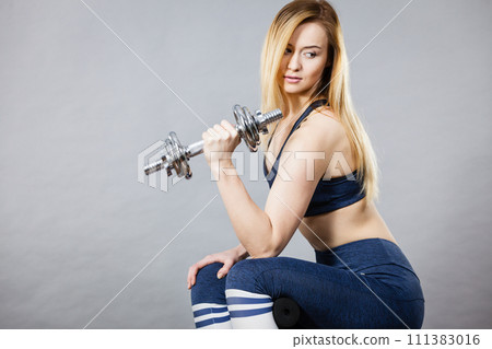 Woman working out at home with dumbbell Woman working out at home with dumbbell 111383016