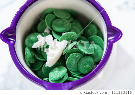 Melting green chocolate chips in a candy melting pot to make cactus cake pops for the Cinco de Mayo celebration. 111383116
