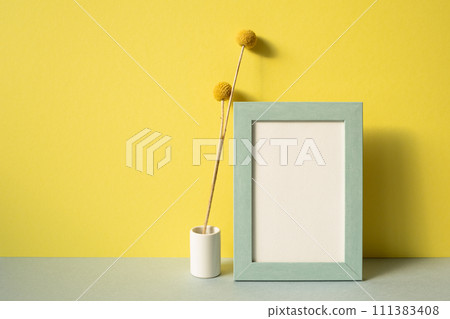Photo frame with vase of dry flower on gray shelf. yellow wall background Photo frame with vase of dry flower on gray shelf. yellow wall background 111383408