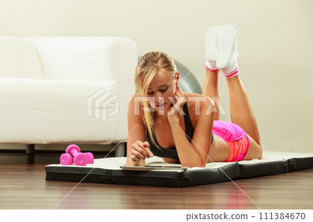 Fit woman lying on floor with tablet pc Fit woman lying on floor with tablet pc 111384670