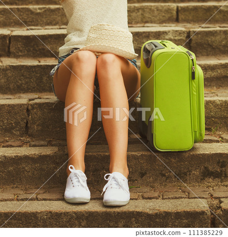 Part body of female tourist with suitcase. 111385229