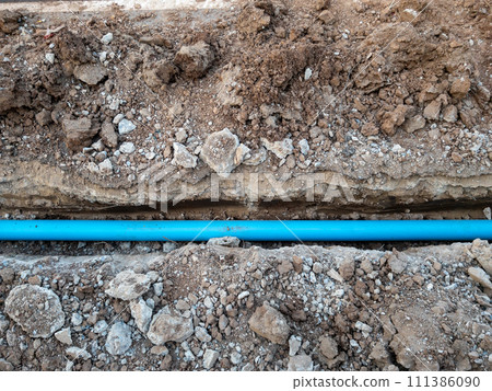 The new PVC pipe is laying in the trench. 111386090
