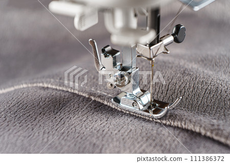 Modern sewing machine with gray velours fabric close up 111386372