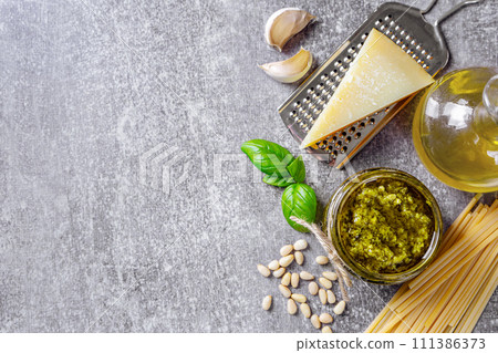 Homemade pesto sauce in small jar and ingredients for pasta on gray concrete background 111386373
