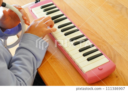 一名小學四年級的女孩正在吹鍵盤口琴。 一名小學四年級的女孩正在吹鍵盤口琴。 111386907