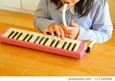 一名小學四年級的女孩正在吹鍵盤口琴。 一名小學四年級的女孩正在吹鍵盤口琴。 111386908