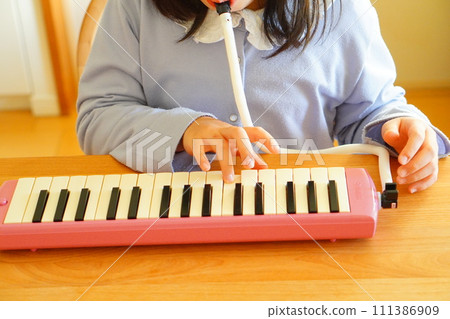 A 4th grade elementary school girl is playing a keyboard harmonica. A 4th grade elementary school girl is playing a keyboard harmonica. 111386909