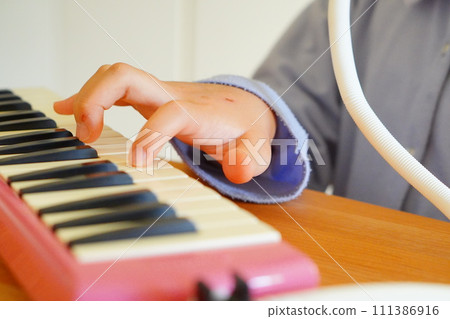 A 4th grade elementary school girl is playing a keyboard harmonica. A 4th grade elementary school girl is playing a keyboard harmonica. 111386916