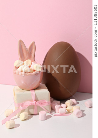 Chocolate eggs with gifts on a pink background Chocolate eggs with gifts on a pink background 111388603