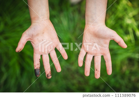 Child shows filthy hands outdoors 111389076