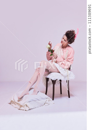Beautiful young woman sitting on chair and painting white rose flower with red nail polish. Making life brighter, giving more passion. Beautiful young woman sitting on chair and painting white rose flower with red nail polish. Making life brighter, giving more passion. 111389691