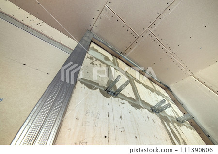 Unfinished brick wall in a room under construction prepared for drywall plates frame installation. 111390606