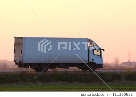 Cargo truck driving on highway hauling goods in evening. Delivery transportation and logistics concept 111390691
