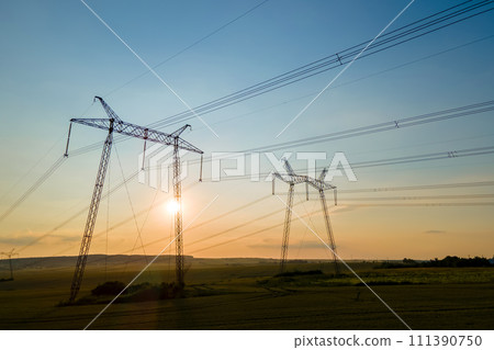 Dark silhouette of high voltage towers with electric power lines at sunrise. 111390750