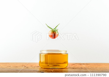 Olive oil in the glass and one red tomato Olive oil in the glass and one red tomato 111390790
