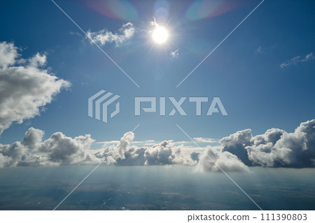 Aerial view from airplane window at high altitude of earth covered with white puffy cumulus clouds 111390803