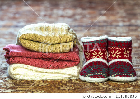 Red shoes with new year pattern and a pile of knitted sweaters 111390839