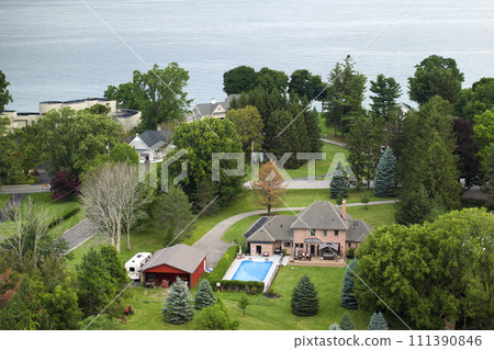 Private residential house in lakeside suburban sprawl area in Rochester, New York. Upscale suburban home with large backyard swimming pool and green grassy lawn in summer season 111390846